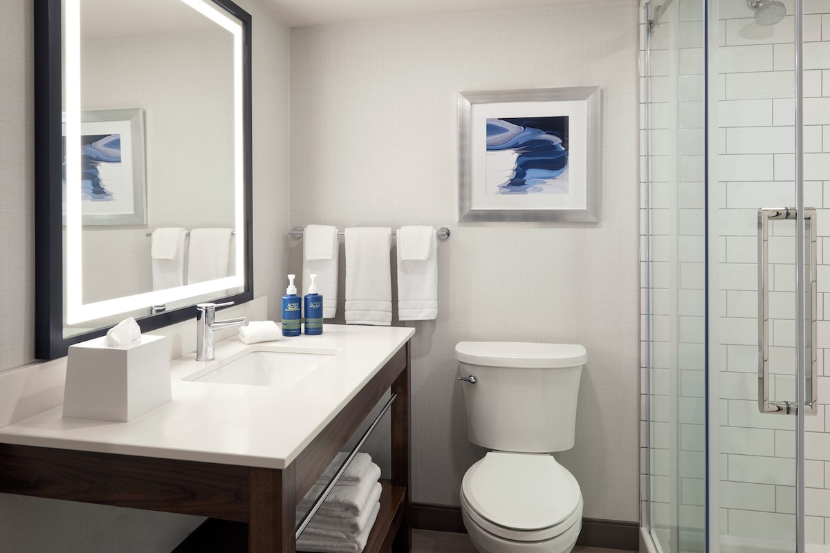 A bathroom with a white sink, mirror, and toilet. There are two framed pictures on the wall.