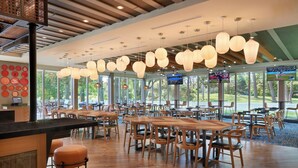 A spacious restaurant with wooden tables and chairs, large windows, and hanging pendant lights. - Four Points by Sheraton Point Edward Sarnia (Sarnia)