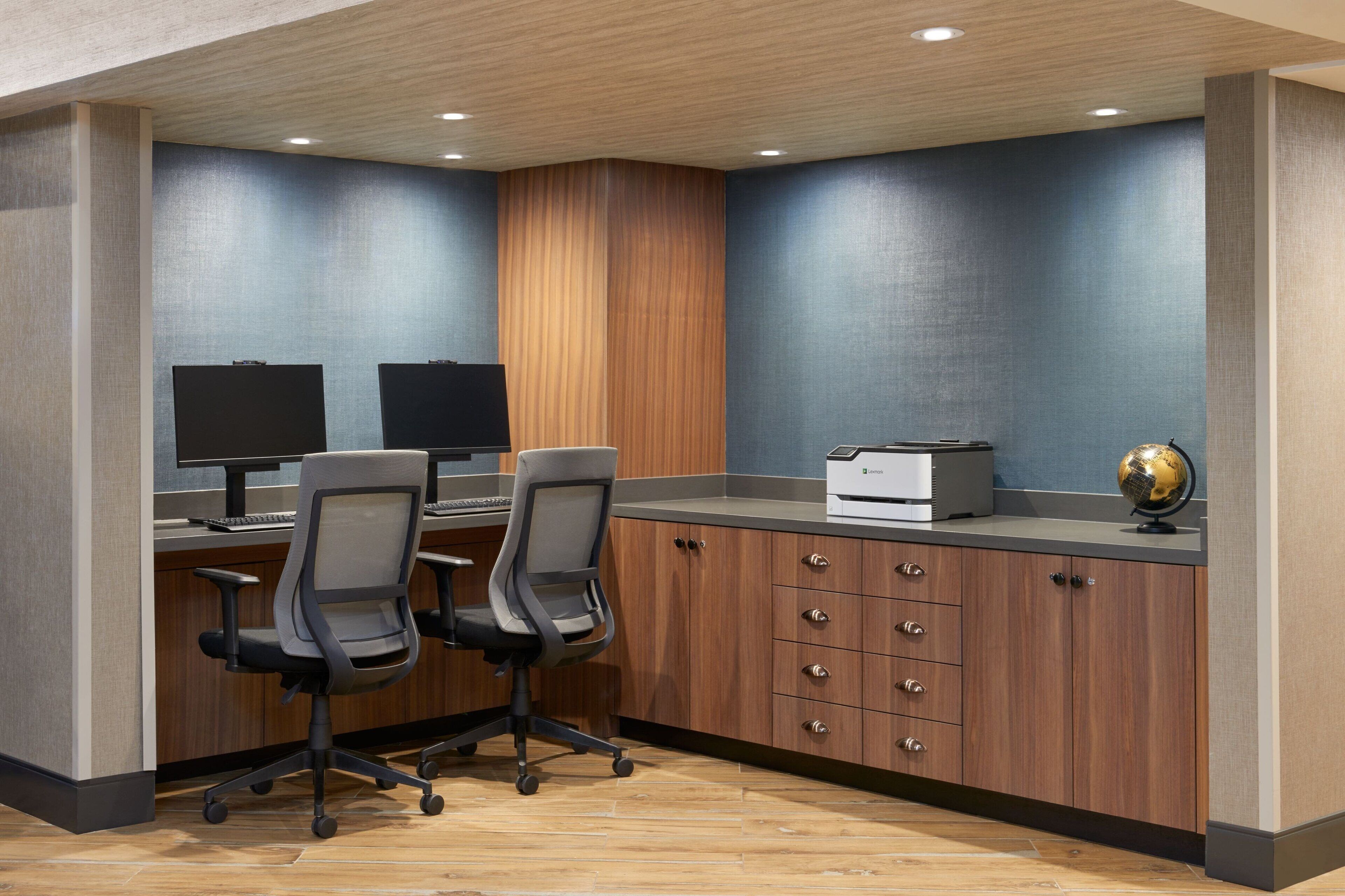 A modern office space with two desks, chairs, a printer, and a globe.