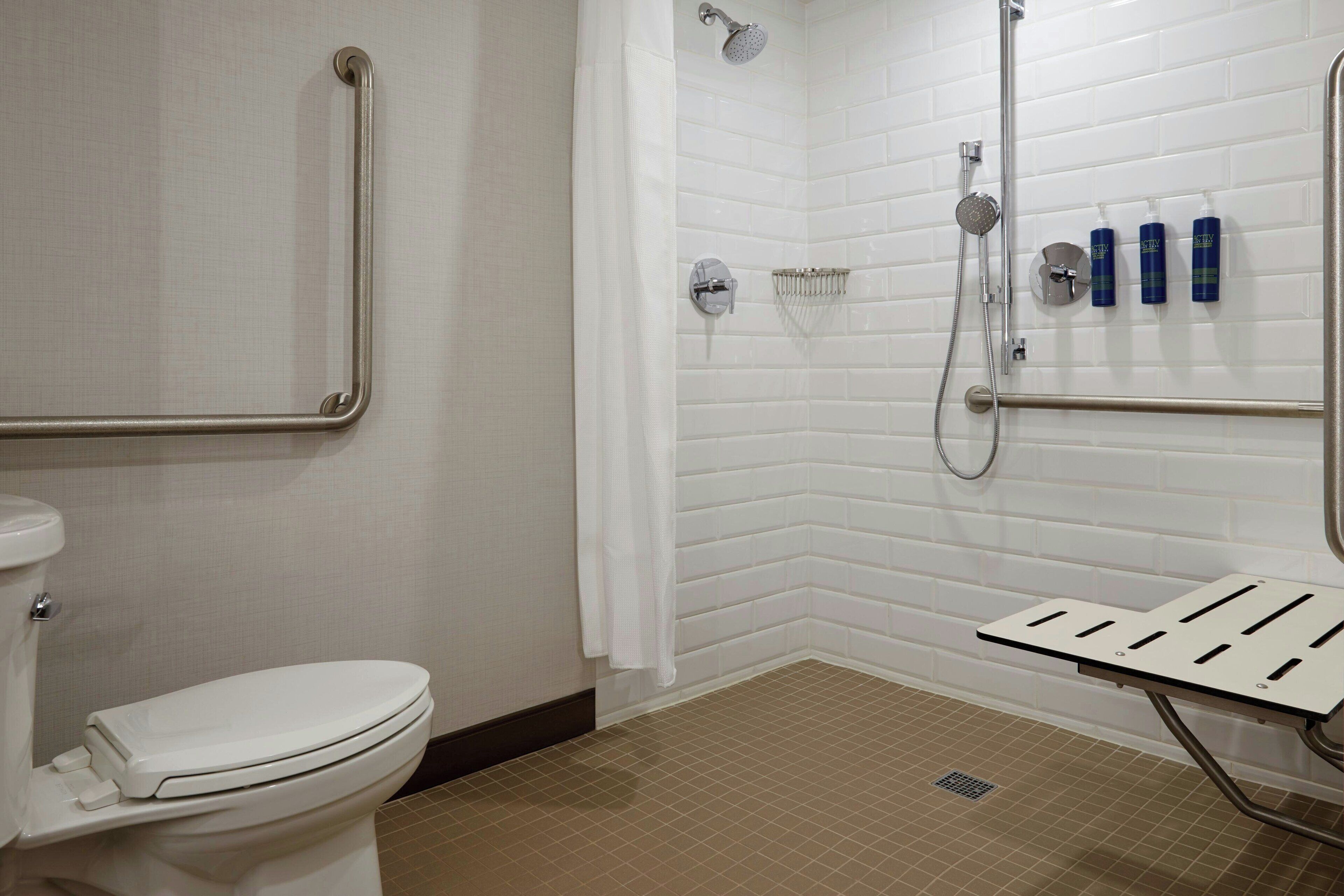 Ein Badezimmer mit Toilette, Dusche inklusive Duschbrause und einer Haltestange.