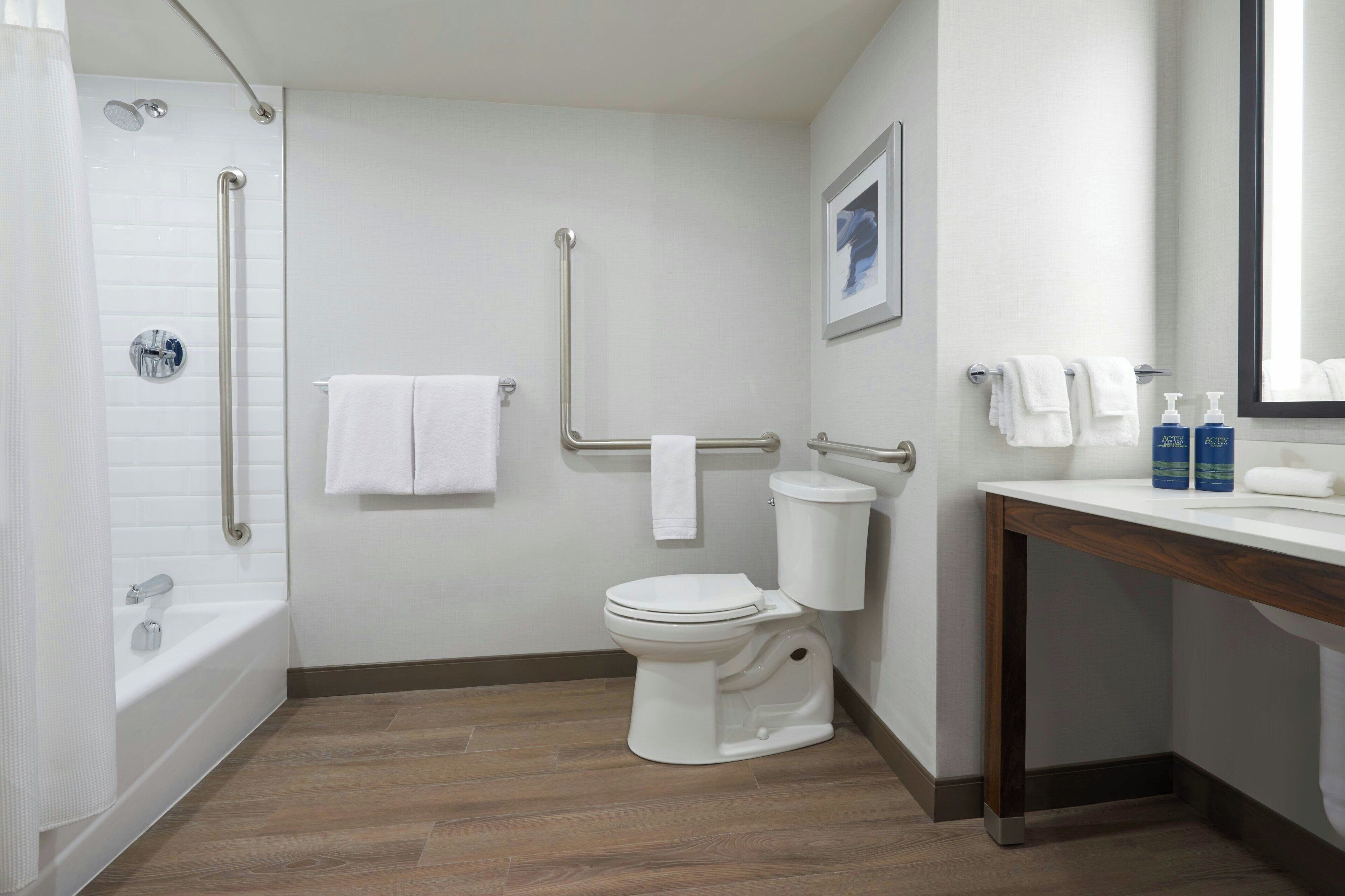 A modern bathroom with a bathtub, toilet, and shower.
