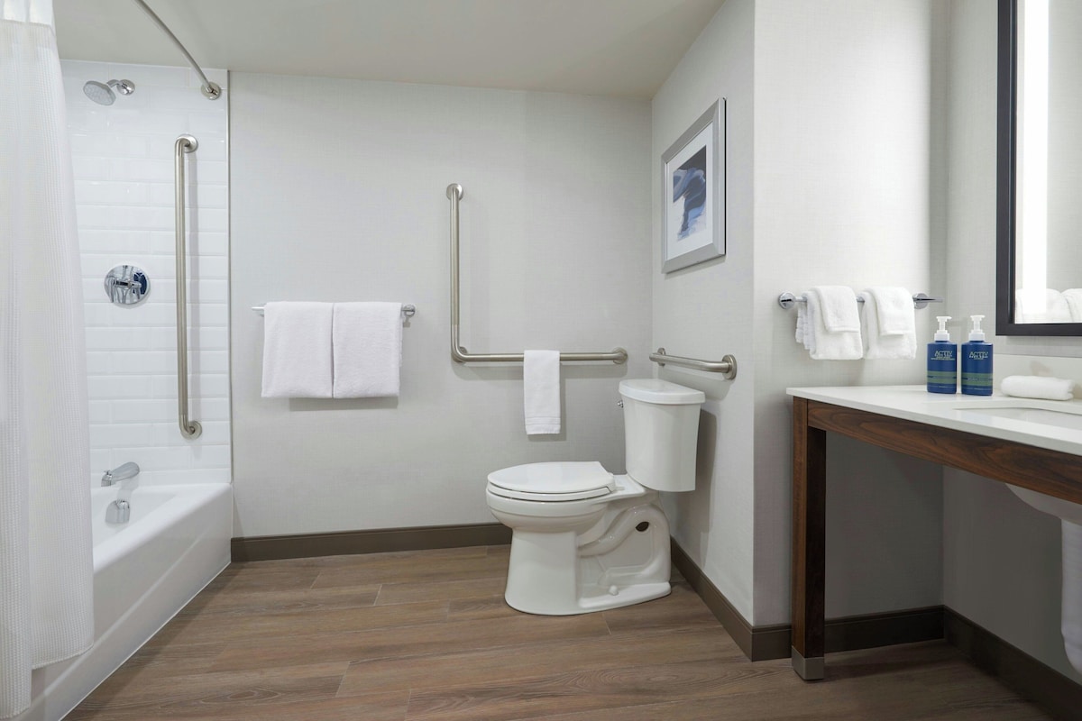 A modern bathroom with a bathtub, toilet, and shower.