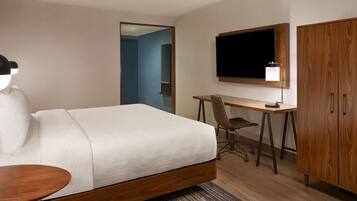 A hotel room with a bed, desk, chair, TV, and wardrobe.