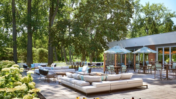 An outdoor patio area with a sofa, chairs, and umbrellas. - Four Points by Sheraton Point Edward Sarnia (Sarnia)