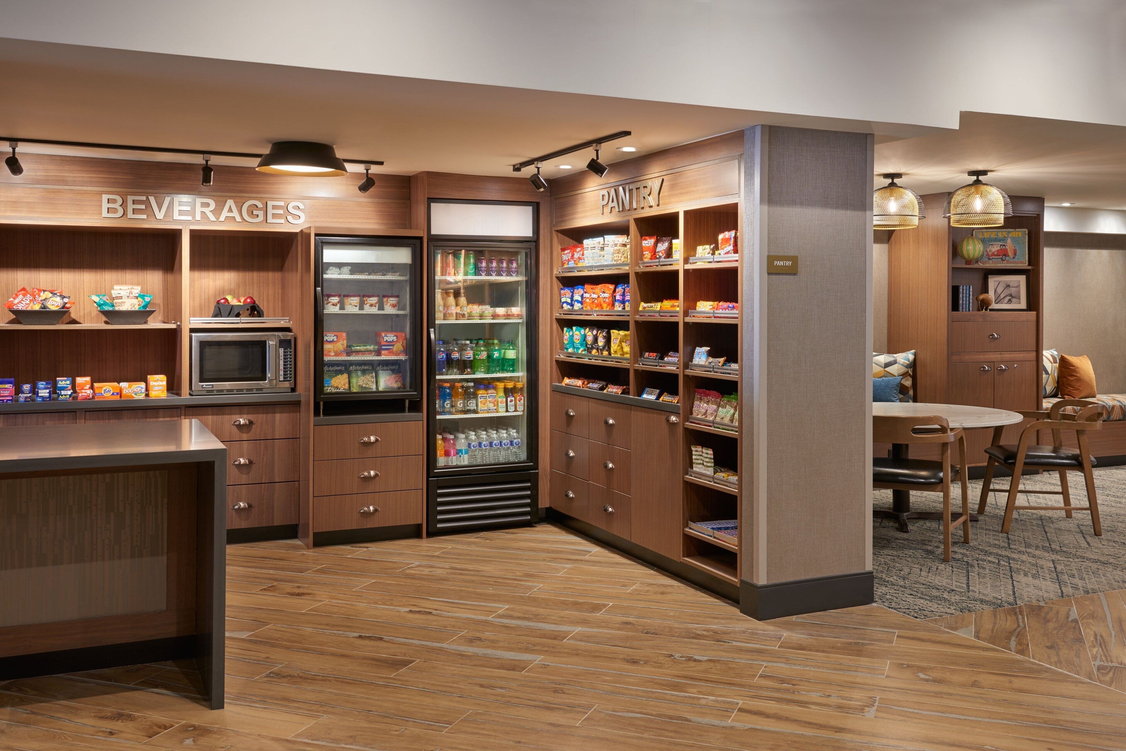 Una kitchenette equipada con microondas, refrigerador y despensa llena de refrigerios y bebidas.