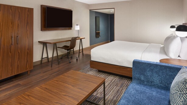A hotel room with a bed, a desk, a chair, a wardrobe, and a television. - Four Points by Sheraton Point Edward Sarnia (Sarnia)