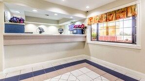 A reception area with a counter, a computer, and a window with a view of the outside.