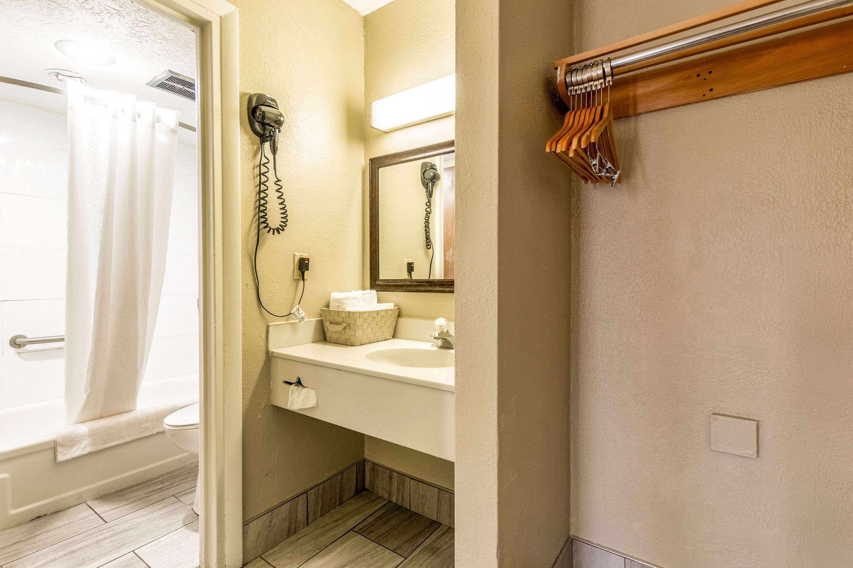 Un baño con ducha, secador de pelo, lavabo y espejo.