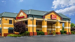 A hotel with a yellow facade, green roof, and two visible signs: "Welcome" and "EconoLodge."