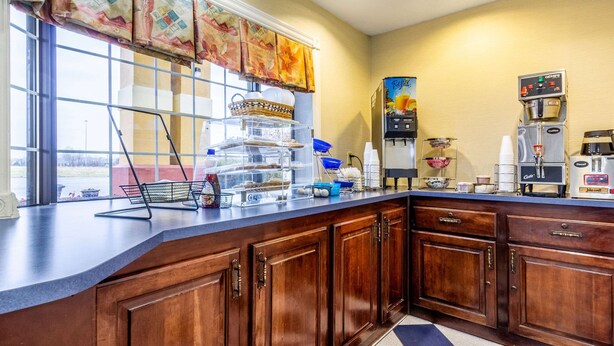 A kitchen with wooden cabinets, a coffee machine, and a window with a view of the outdoors.