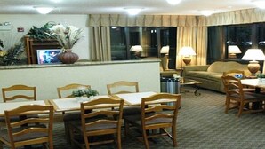 Ein Hotel-Essbereich mit einem langen Tisch und Stühlen, einer Couch und einem Fernsehbildschirm.