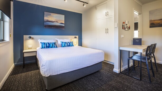 Una habitación de hotel moderna con una cama grande, un escritorio y una silla.