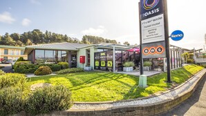 Un hotel llamado 'The Oasis Riverside' con un cartel que indica que ofrece juegos, un bistró, bar deportivo y alojamiento.
