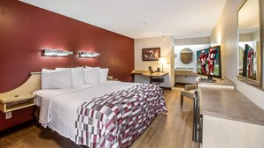 Habitación de hotel con cama, mesitas de noche, escritorio, silla, televisión y espejo.