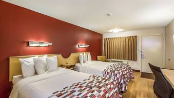 A hotel room with two beds, a desk, a chair, a window with curtains, and a door.