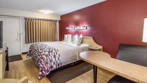 A hotel room with a bed, a desk, a chair, a wardrobe, and a door. - Red Roof Inn Detroit - Plymouth/ Canton (Plymouth)