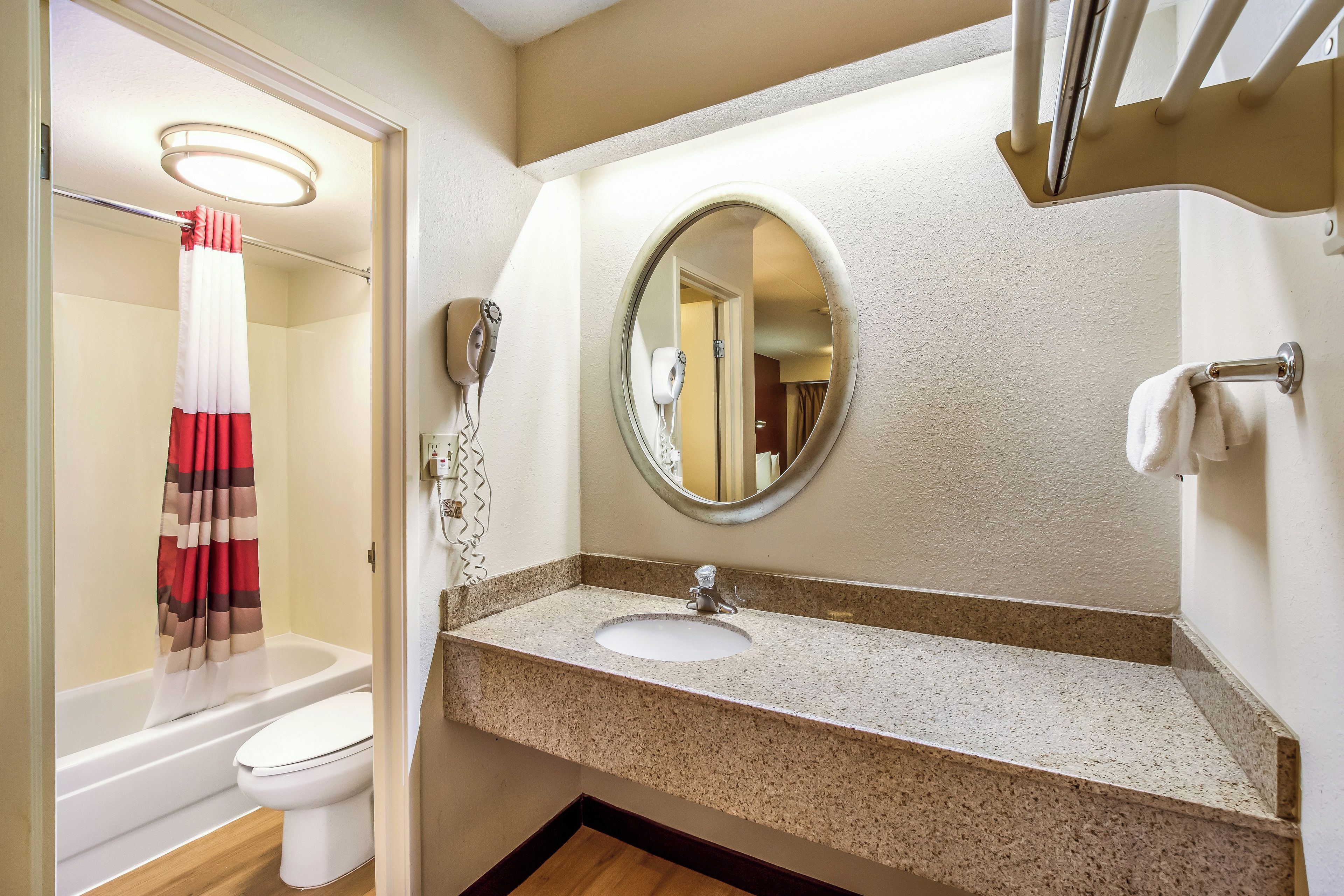 A bathroom with a white toilet, a sink with a granite countertop, a mirror, and a shower curtain.