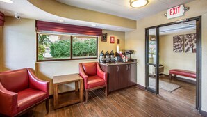 A hotel lobby with a seating area, a coffee station, and an exit sign. - Red Roof Inn Detroit - Plymouth/ Canton (Plymouth)