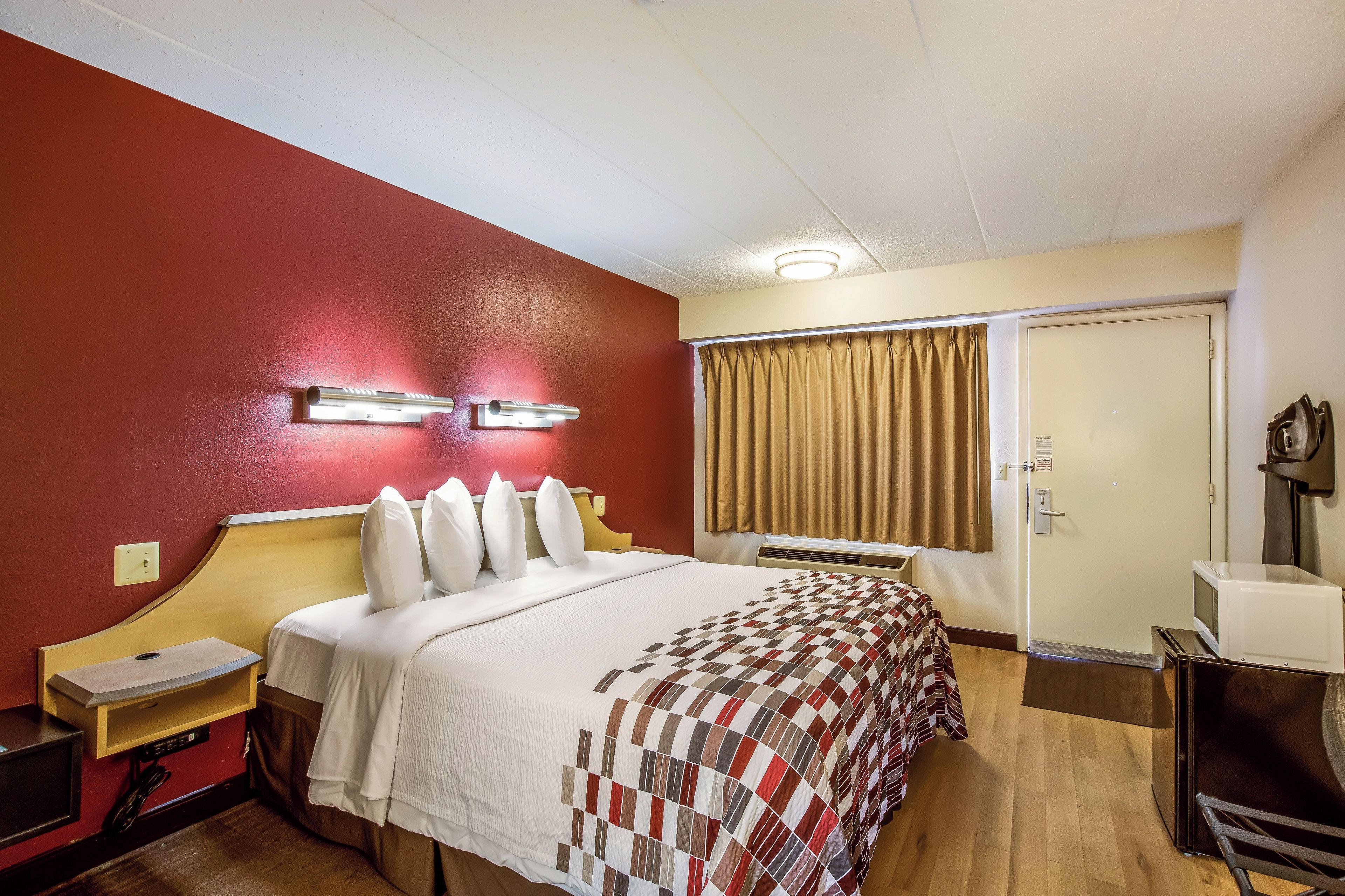 A hotel room with a bed, a desk, a microwave, and a wardrobe.