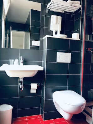 A modern bathroom with a white sink, toilet, and a towel rack. - Alfred Hotels Paris Lecourbe (Paris)