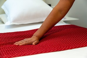 A hand resting on a red polka-dotted bedspread. - Alfred Hotels Paris Lecourbe (Paris)