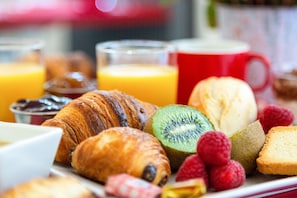 A breakfast spread with croissants, kiwi, raspberries, and juice. - Alfred Hotels Paris Lecourbe (Paris)