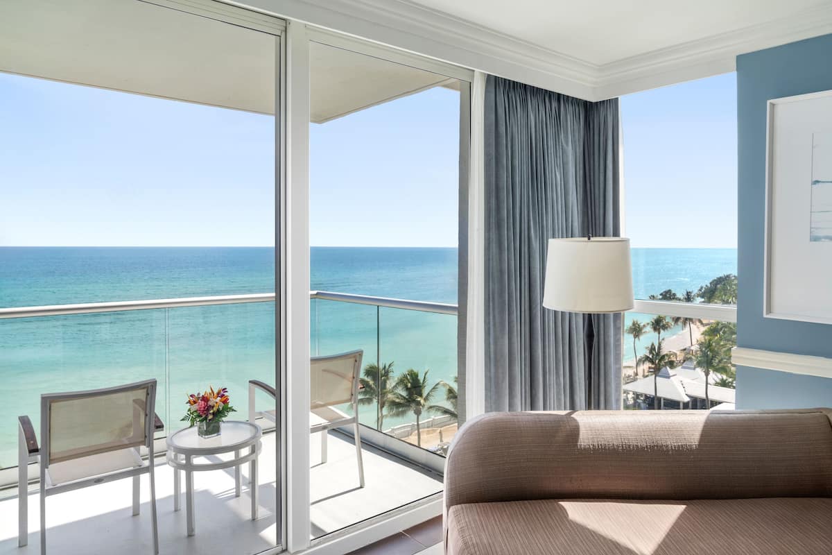 Un balcone con vista sull'oceano, un tavolo con fiori e un divano.