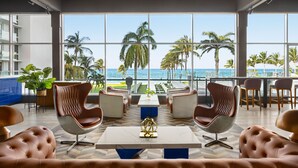 Eine moderne Lounge mit Meerblick, ausgestattet mit Ledersesseln, einem Marmortisch und einer blauen Akzentwand.