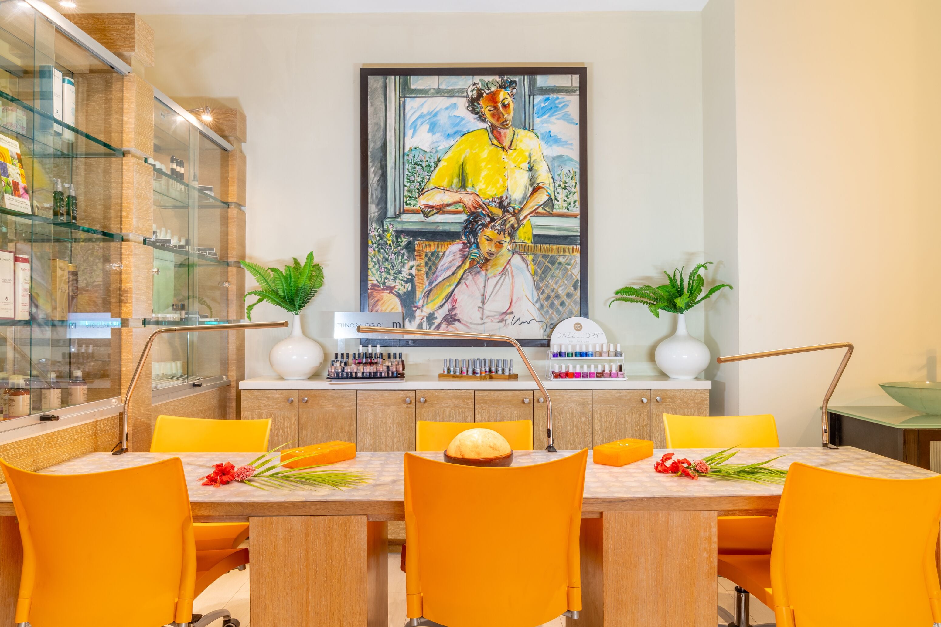 A dining area with a glass display case, a painting, and a table with chairs.