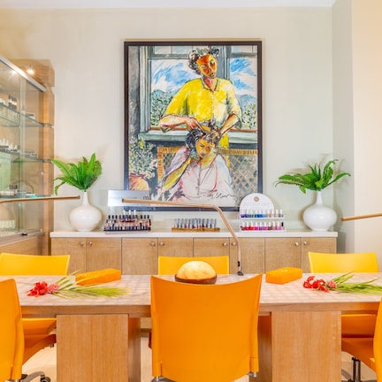 A dining area with a glass display case, a painting, and a table with chairs.