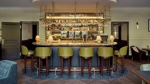 Eine Bar mit einer gebogenen Theke, mehreren Hockern und einer Auswahl an Flaschen und Gläsern.
