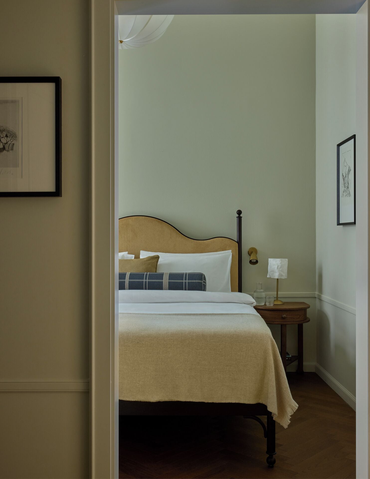 Ein Schlafzimmer mit einem Bett, Kissen, einem Nachttisch mit Lampe und einem gerahmten Bild an der Wand.