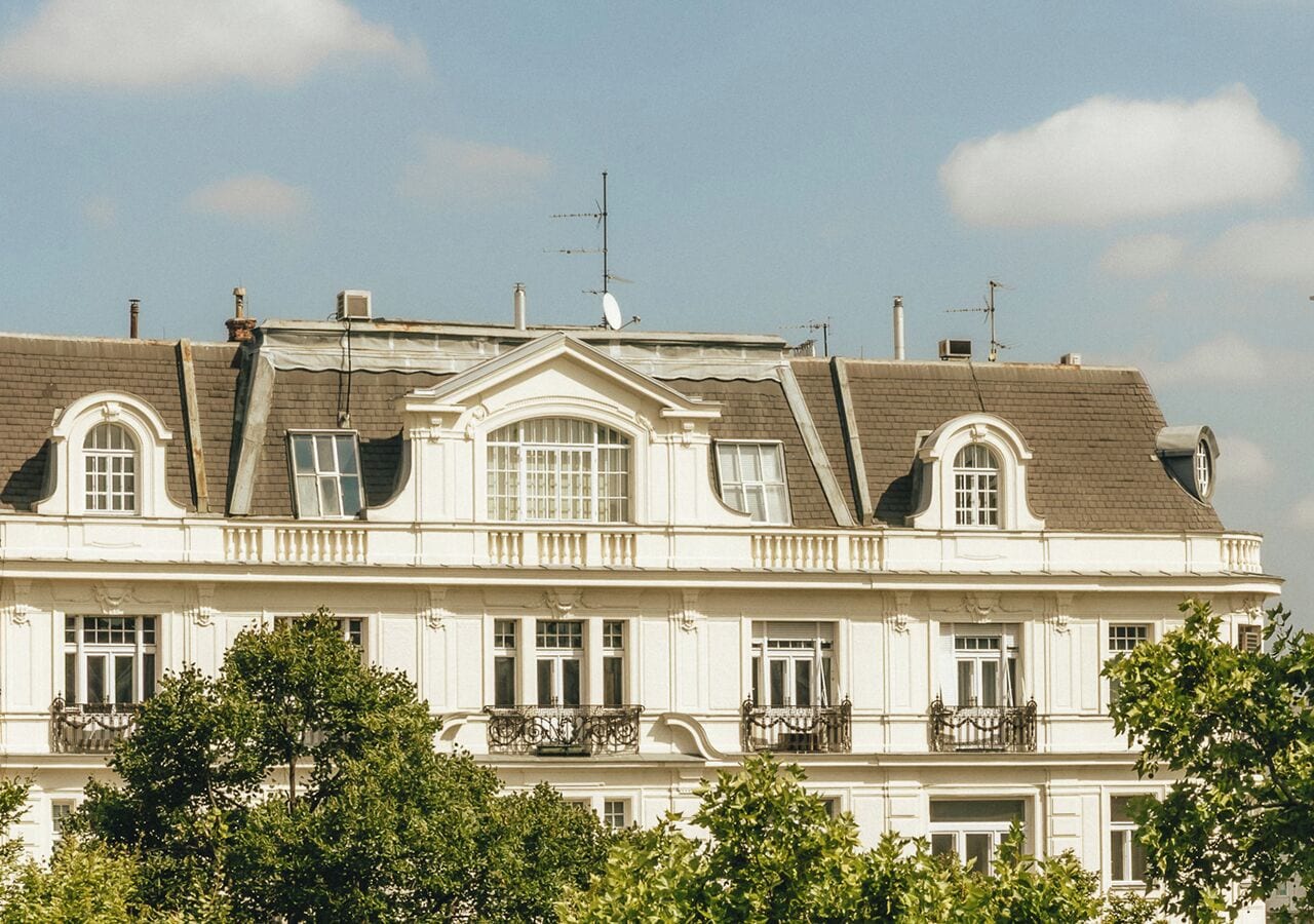 Un edificio de varios pisos con fachada simétrica, ventanas amplias y balcones.