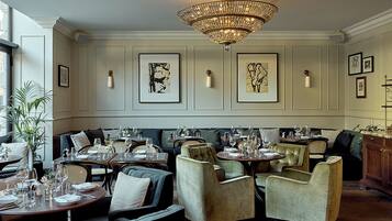 A dining area with multiple tables set for dining, cushioned seating, and artwork on the walls.