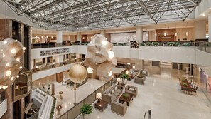 A multi-level hotel lobby with a high ceiling, modern furniture, and decorative lighting fixtures. - Athenaeum InterContinental by IHG (Athens)
