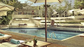 A poolside area with lounge chairs, a wooden table, and umbrellas.