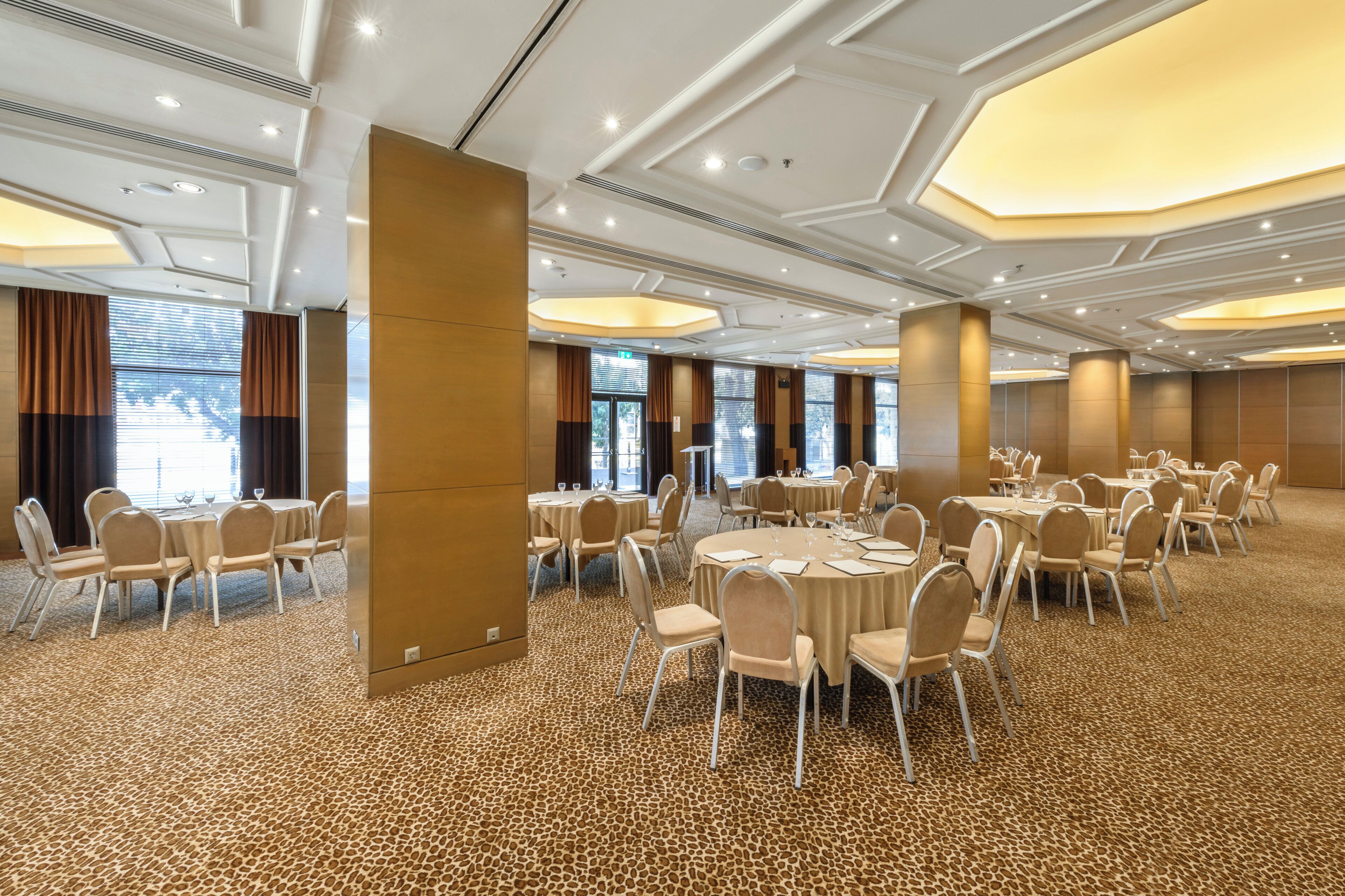 A conference room with round tables, chairs, and a patterned carpet.