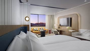A hotel room with a large bed, a sofa, a TV, and a view of a cityscape.