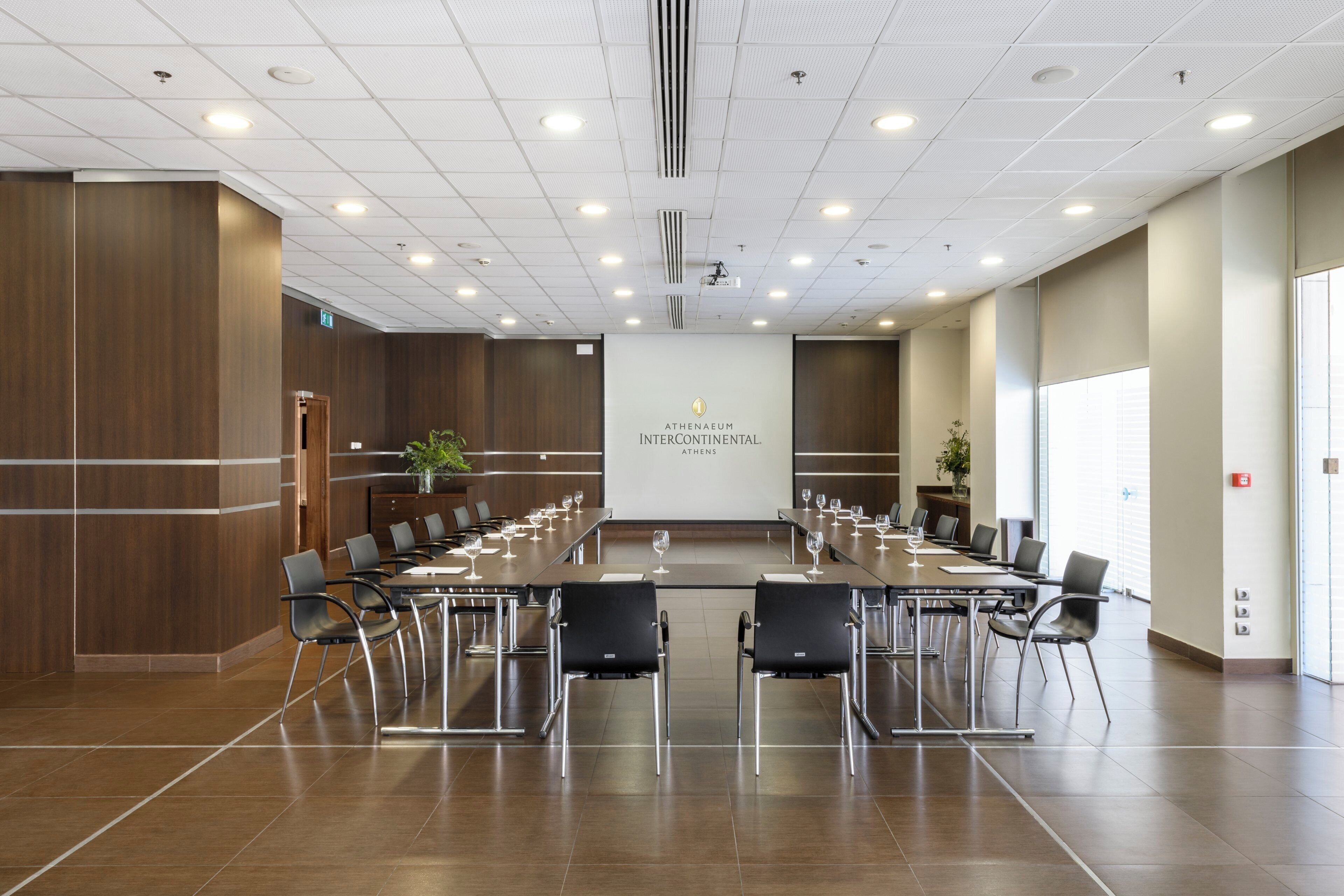 A conference room with a long table, chairs, and a logo on the wall.