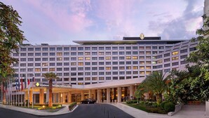A modern hotel with a symmetrical facade, multiple floors, and a prominent entrance with a canopy.