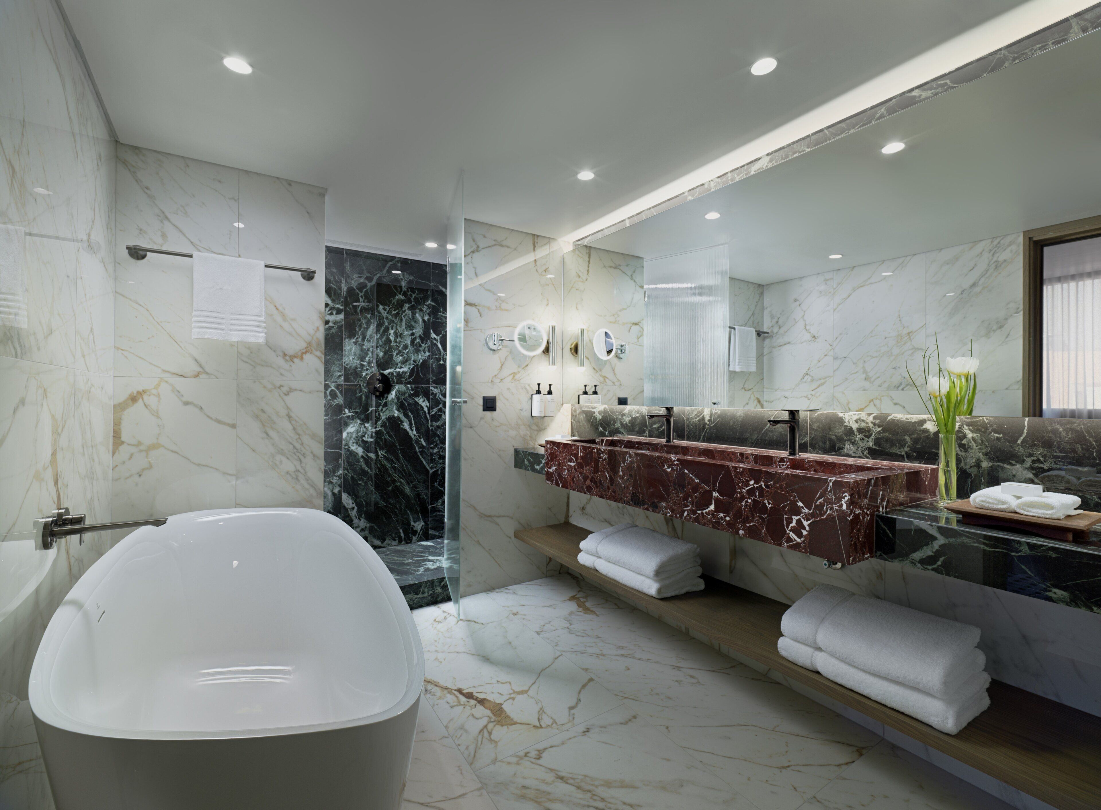 A modern bathroom with a freestanding bathtub, a glass-enclosed shower, and a marble vanity with a large mirror.