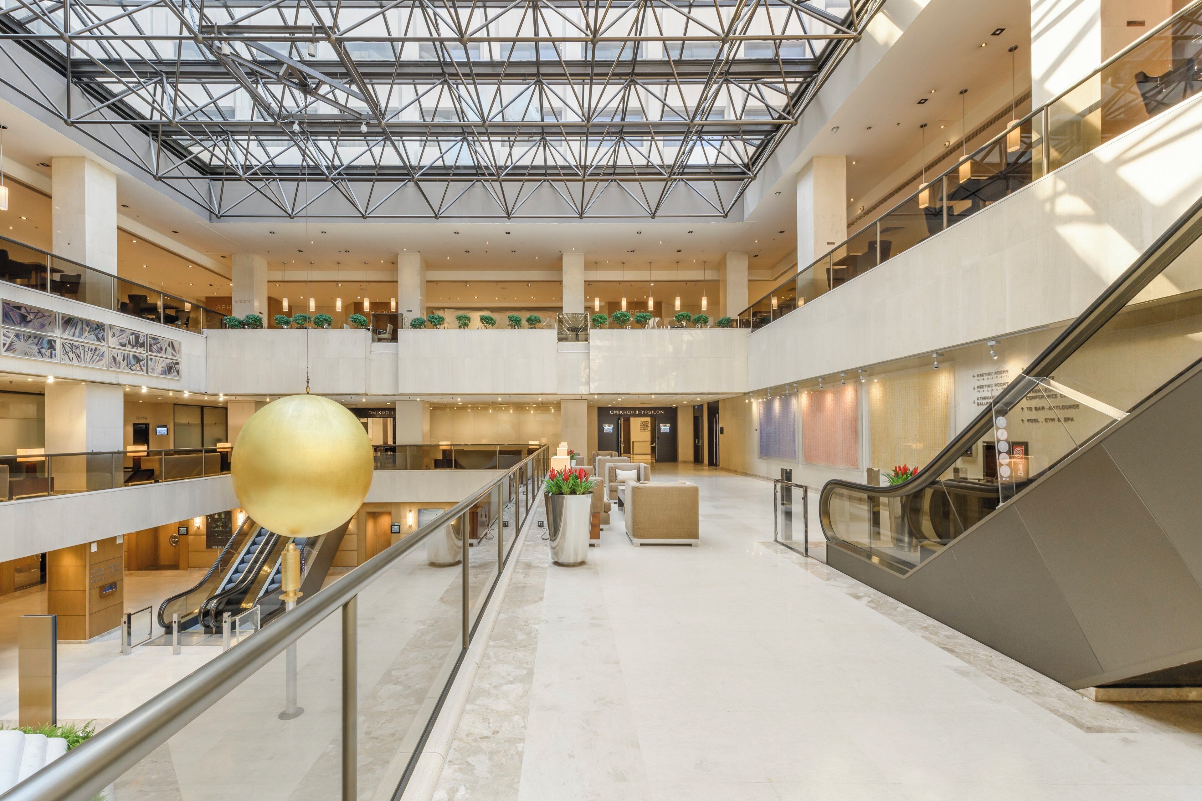 A multi-level atrium with a glass ceiling, escalators, and a central decorative sphere.