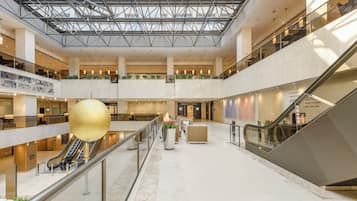 A multi-level atrium with a glass ceiling, escalators, and a central decorative sphere.