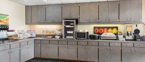 A commercial kitchen with grey cabinets, a microwave, and a coffee machine.