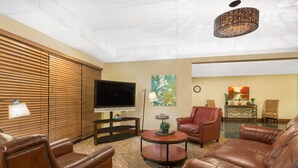 Una sala de estar con sofás de cuero, televisor, mesa de centro y una lámpara decorativa.