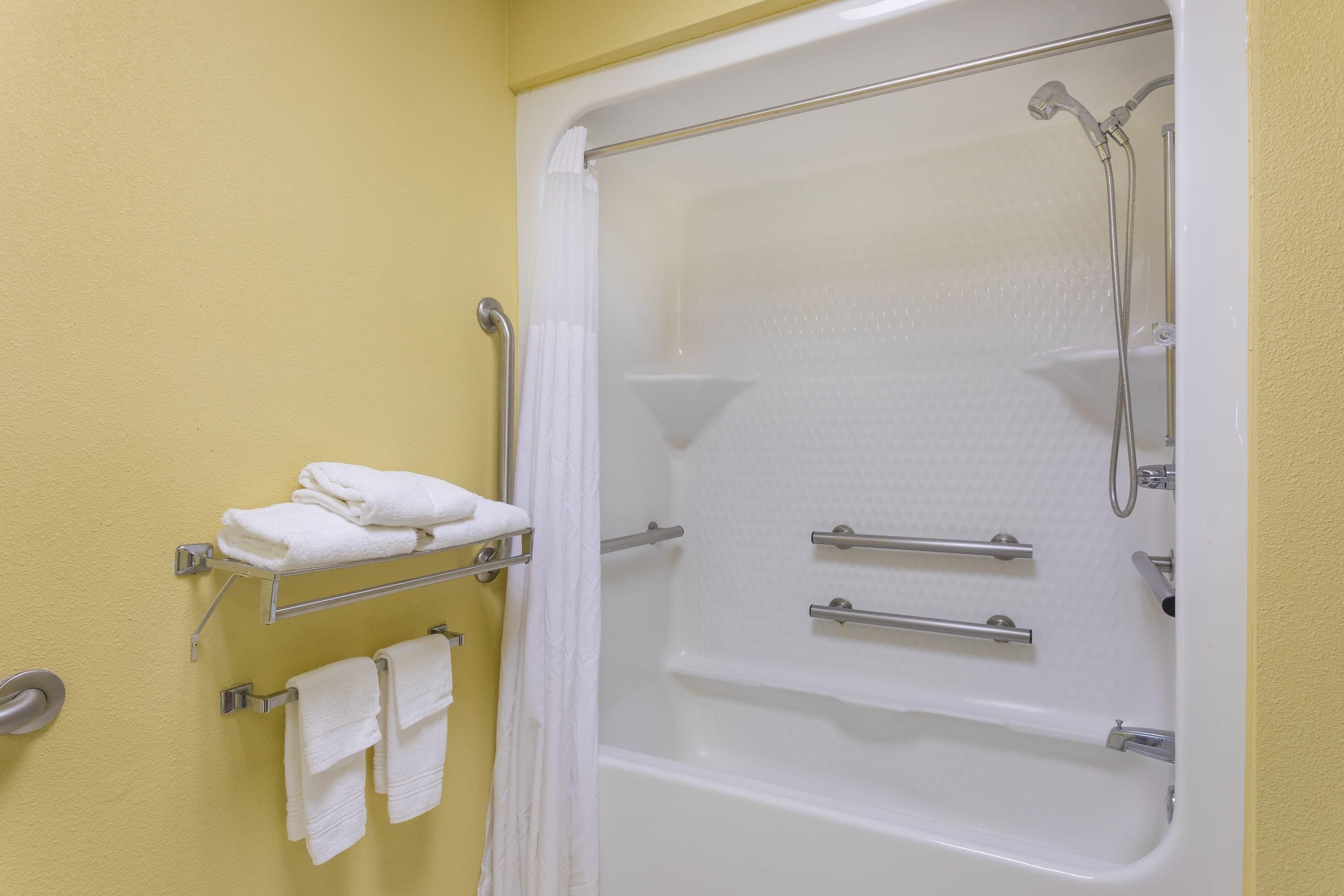 A bathroom with a bathtub, a shower, and towel racks.
