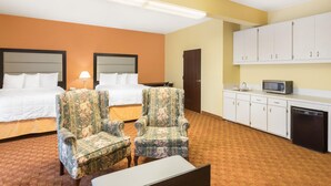 Habitación de hotel con dos camas, un escritorio, una silla, microondas y lavavajillas.