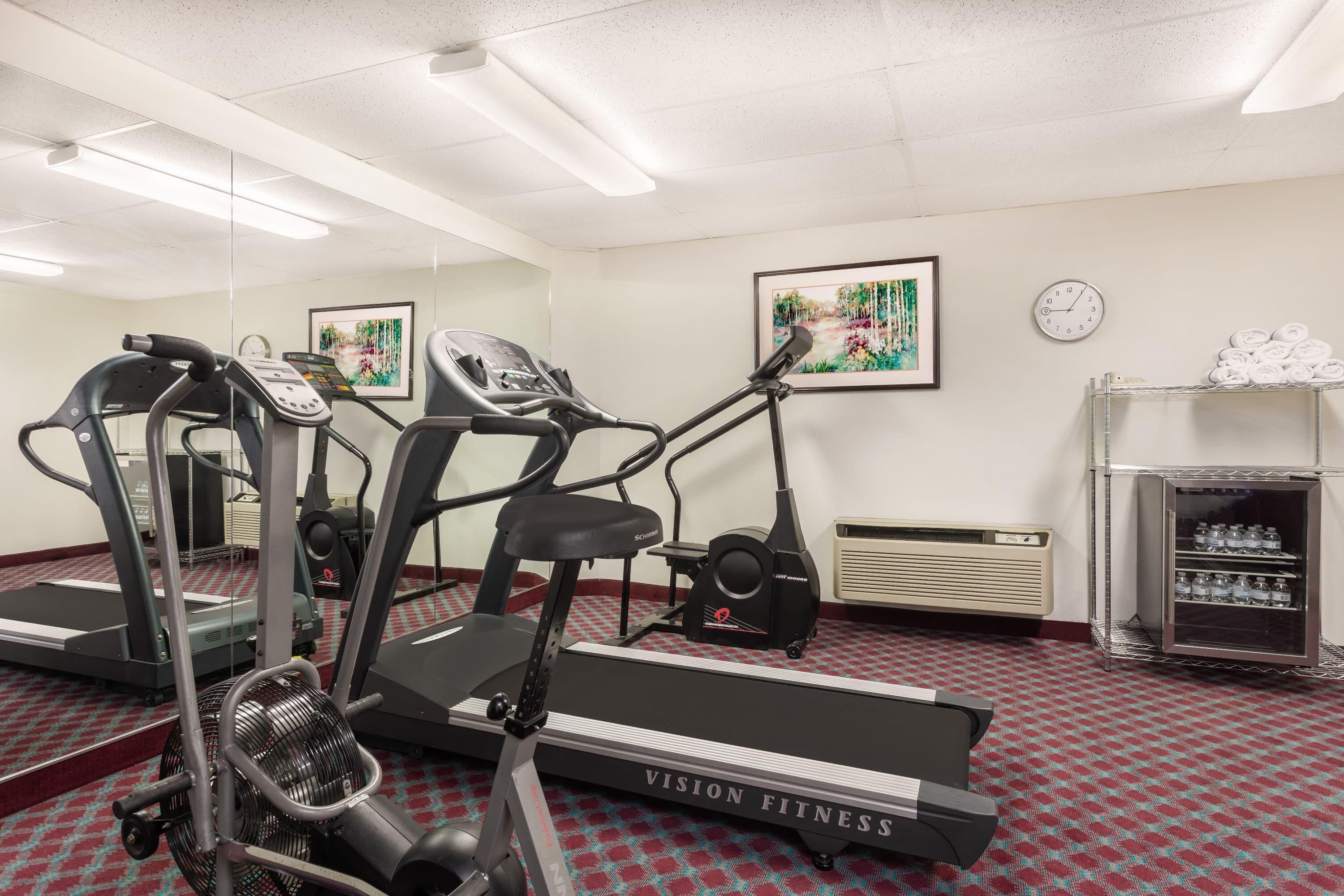 A fitness center with treadmills, a fan, a clock, and a water dispenser.