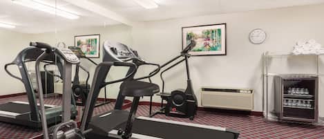 A fitness center with treadmills, a fan, a clock, and a water dispenser.