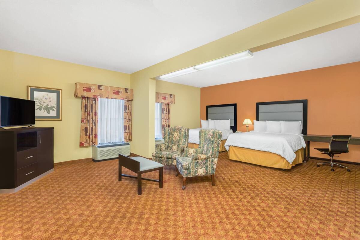 A hotel room with a bed, a desk, a chair, a television, and a window with curtains.